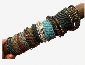Multiple beaded bracelets on a wooden stick against a white background