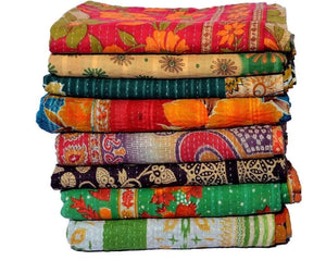 Stack of colorful patterned kantha quilts on a white background
