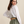 Woman wearing a white blouse and green skirt against a beige background