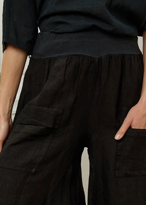 Person wearing black pants with cargo pockets against a neutral background