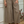 Person wearing beige linen pants standing in a room with a decorative wall and plant.