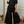 Woman wearing a black outfit with wide-leg pants in a room with decorative elements.