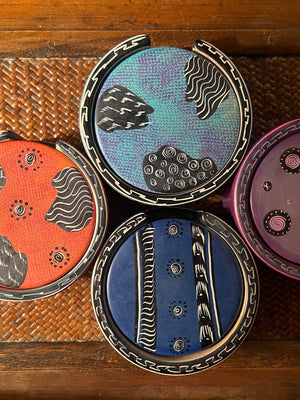 Four round containers with colorful lids on a woven surface