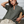 Woman wearing a green henley shirt and beige pants sitting on a wicker chair.