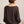 Person wearing a brown dolman sweater with a neutral background