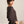 Woman wearing a brown dolman sweater against a plain background
