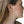 Close-up of a person wearing a gold hoop earring with a neutral background