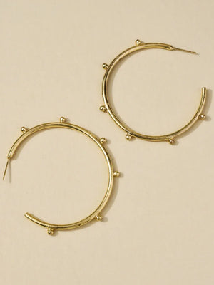 Gold hoop earrings on a beige background