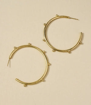 Gold hoop earrings on a beige background