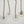 Five necklaces with circular pendants featuring different stones on a white background