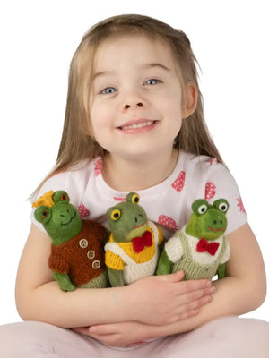 Young girl holding three knitted frog toys against a white background