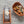 Wood and metal cheese grater with a block of cheese next to a wooden bowl of food on a wooden surface