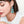 Close-up of a woman wearing turquoise earrings with a plain background