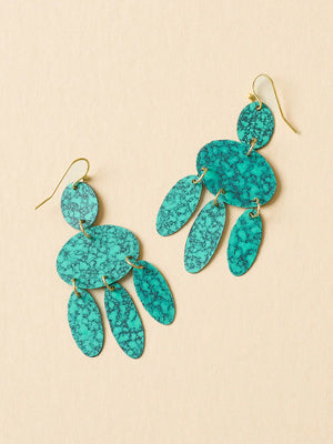 Turquoise earrings with gold accents on a beige background