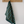 Striped green towel hanging on a wooden hook against a white wall