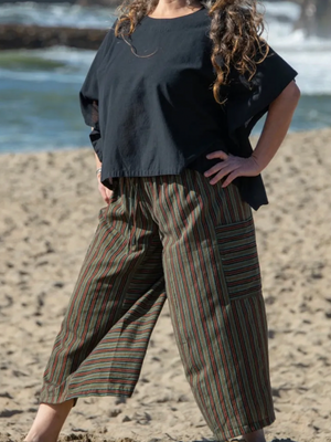 Person wearing a black top and green and red striped pants on a beach