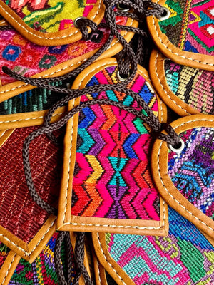 Colorful embroidered fabric luggage tags with geometric patterns and brown leather accents.