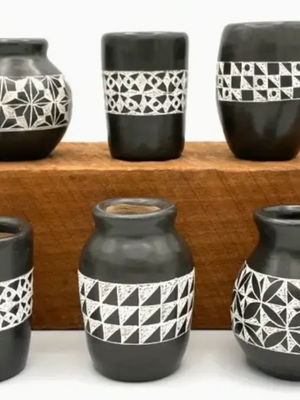 Set of black ceramic vases with geometric patterns on a wooden shelf.
