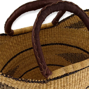 Close-up of a woven tote basket with a brown handle on a white background