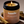 Kandu Palo Santo Tobacco candle in a jar with a lit wick, surrounded by wooden sticks on a beige background.
