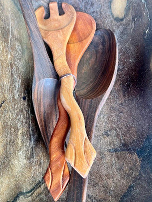 Wooden utensils with snake shaped handles on a textured surface