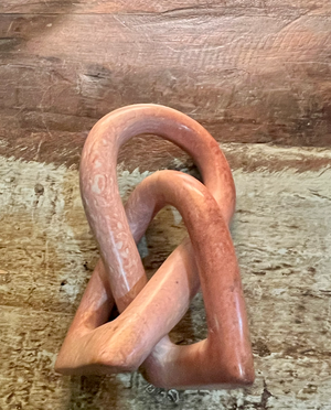 Pink ceramic sculpture on a wooden surface