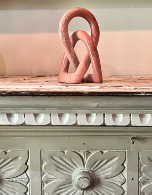 Decorative pink sculpture on a textured surface with floral patterns