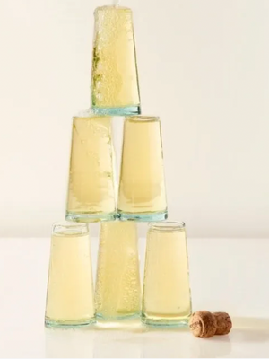 Clear glass tumblers stacked in a pyramid with a cork on a light background