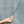 Hand holding a black incense stick against a gray concrete wall