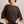 Woman wearing a brown dolman sweater against a neutral background