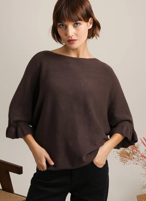 Woman wearing a brown dolman sweater against a neutral background