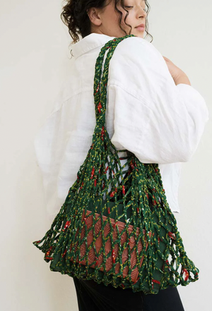 Person wearing a green macrame bag on a plain background