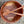 Wooden salad bowl with two wooden utensils on a speckled countertop