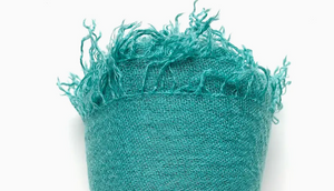 Turquoise fabric with frayed edges on a white background