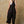 Woman wearing a black overalls and white top against a beige wall