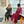 Two women in patterned robes sitting on a claawfoot tub in a bathroom with large windows.