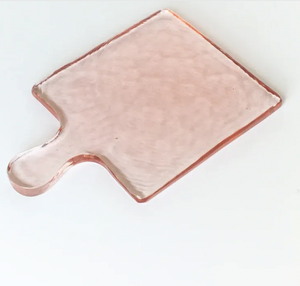 Textured pink glass cutting board on a white background