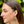 Close-up of a woman wearing colorful earrings with a blurred green background