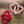 Two heart-shaped objects, one red and one beige, on a wooden surface.