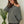 Woman wearing a gray off-shoulder sweater with a plant in the background