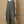 Person wearing a green overalls holding a woven bag against a textured wall.