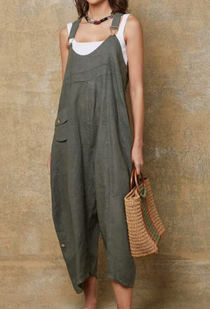 Person wearing a green overalls holding a woven bag against a textured wall.