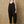 Woman wearing black overalls against a beige wall