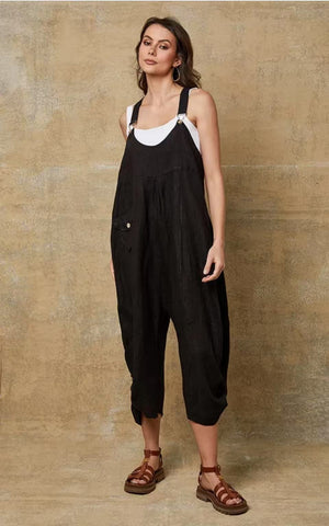 Woman wearing black overalls against a beige wall