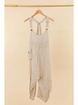 Beige overalls hanging on a wooden hanger against a beige background