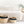 Two woven baskets with black tassels on a white surface in front of a bed.