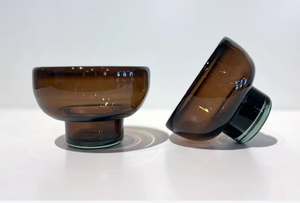 Two brown glasses on a white surface with a light gray background
