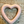 Heart-shaped object with a pinkish hue on a textured surface