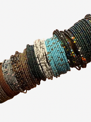 Multiple beaded bracelets on a wooden stick against a white background