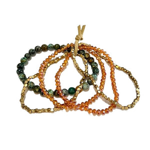 Set of beaded bracelets in green, orange, and gold on a white background